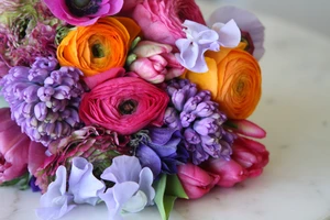 A colorful bouquet of pink, orange, purple, and lavender flowers on a white surface.