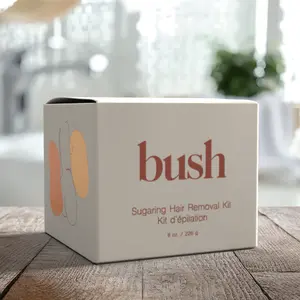 A box labeled 'bush Sugaring Hair Removal Kit' sits on a wooden table in a bright room.