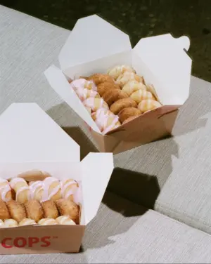 Two open boxes of assorted cream-filled pastries placed on a light-colored cushioned surface.
