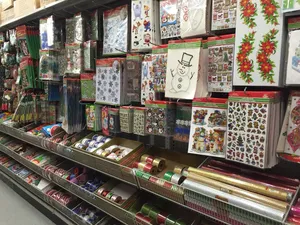 Store aisle with shelves of Christmas-themed stickers, gift wrap, and decorative supplies.