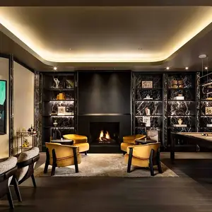 Modern living room with a fireplace, bookshelves, four yellow chairs, and warm ambient lighting.