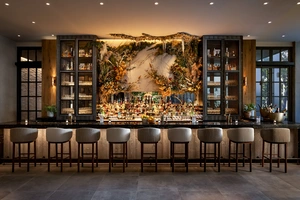 Elegant bar with six chairs, backlit shelves, and a decorative mural behind the counter.