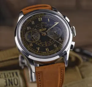 A vintage wristwatch with a black dial, gold markings, and a brown leather strap.