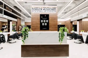 Modern barbershop interior with a front desk, chairs, mirrors, and MEN ZONE BARBERSHOP sign above.