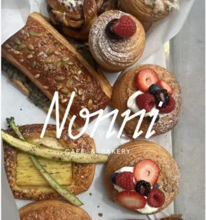 Assorted pastries topped with berries and seeds in a box, with 'Nonni Cafe & Bakery' text overlay.