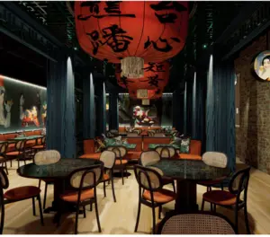 A stylish restaurant interior with round tables, red chairs, and large red lanterns hanging from the ceiling.