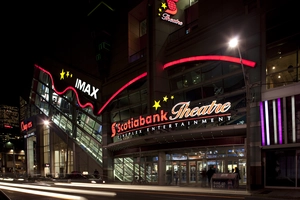 Night view of Scotiabank Theatre with IMAX sign, bright lights, and people entering the building.