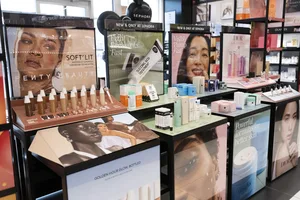 Display tables with various beauty and skincare products arranged in a Sephora store.