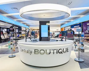 Modern beauty boutique counter in a bright, well-lit store with beauty products displayed in the background.