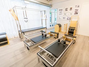 Bright Pilates studio with reformer machines and other Pilates equipment on a light wood floor.